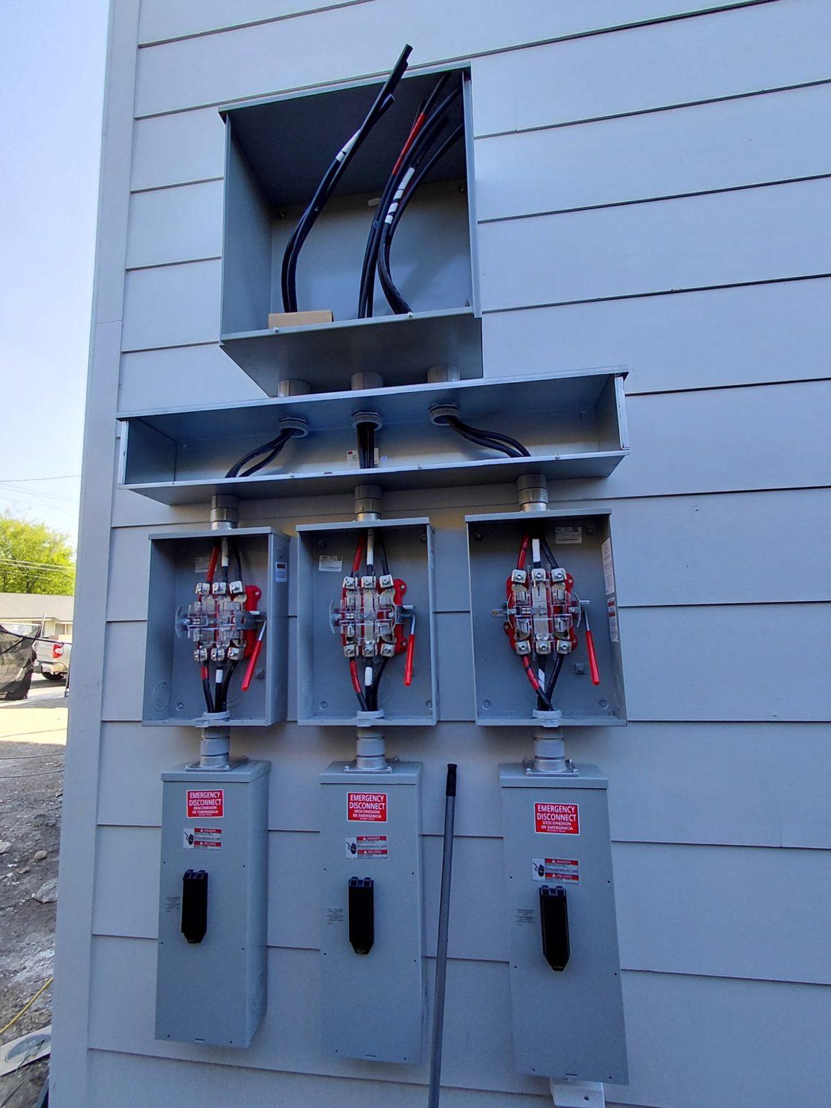 Completed three-unit meter stack with emergency disconnect switches on an apartment building exterior
